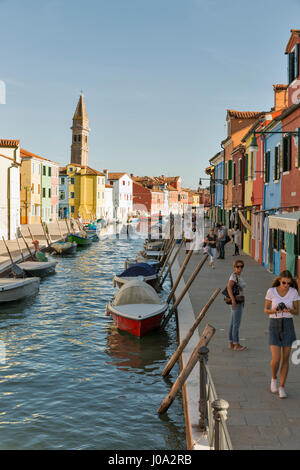 BURANO, Italia - 22 settembre 2016: turistico non riconosciuto a piedi lungo il canale tipico con barche ormeggiate e torre pendente. Burano è un'isola nelle vene Foto Stock