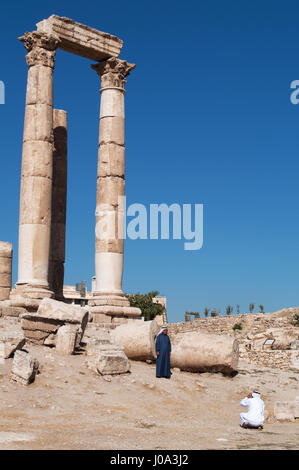Uomini musulmani davanti alle rovine del tempio di Ercole, la più importante struttura romana nella cittadella di Amman, il sito archeologico Foto Stock