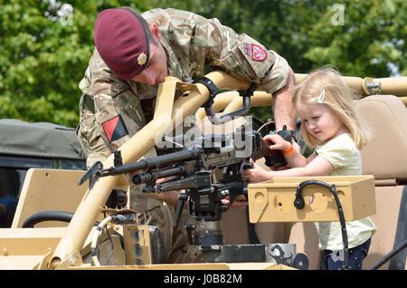 Tatuaggio militare COLCHESTER ESSEX REGNO UNITO 8 Luglio 2014: piccola ragazza essendo mostrato mitragliatrice da soldato Foto Stock