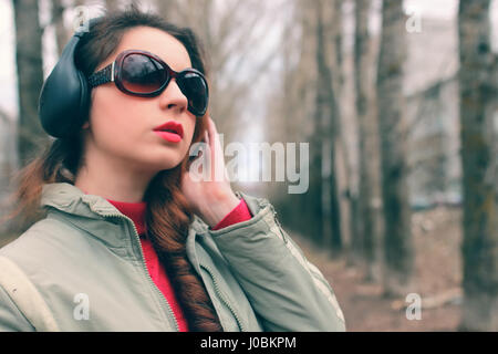 Ragazza nel parco con le cuffie Foto Stock