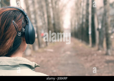 Ragazza nel parco con le cuffie Foto Stock