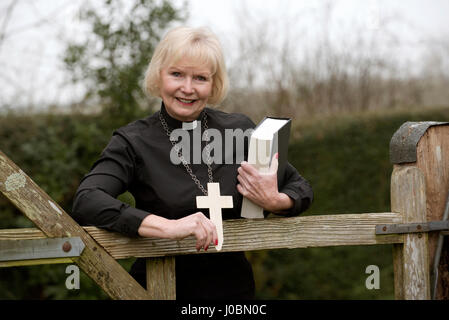 Donna anziana vicario facendo una chiamata a casa nella sua parrocchia nella campagna inglese Foto Stock
