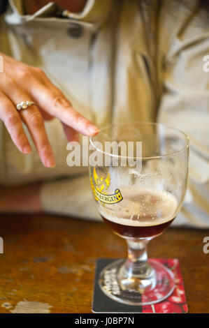 La donna rivolta a vuoto in vetro di birra a la Mort Subite Tavern di Bruxelles Foto Stock