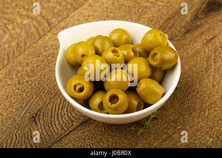 Olive farcite in heap la ciotola su uno sfondo di legno Foto Stock