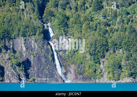 Una barca di fronte ad una cascata sul lago Puelo in Tagua Tagua riserva, Patagonia, Cile Foto Stock