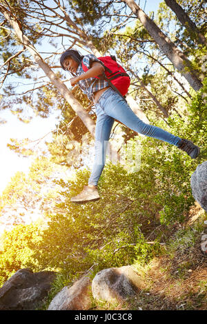 Giovane donna, escursionismo, saltando da una roccia per un altro, Cape Town, Sud Africa Foto Stock