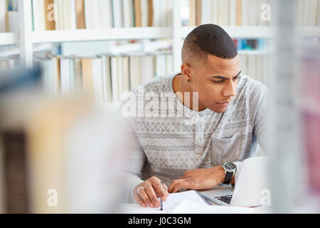 Uno studente universitario che lavorano in biblioteca Foto Stock