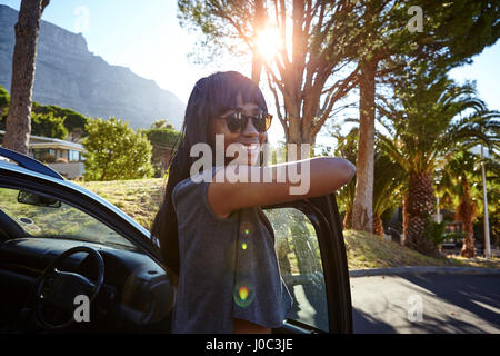 Ritratto di giovane donna in piedi accanto a AUTO, poggiando sulla portiera aperta Foto Stock
