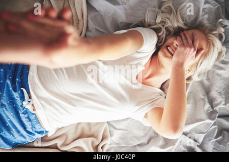 Donna sdraiata sul letto, l'uomo tira fuori il suo letto, vista in elevazione Foto Stock