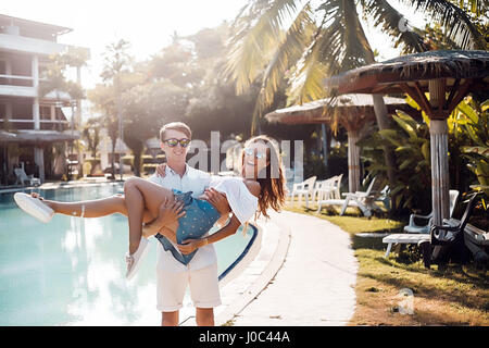 Giovane ragazza di trasporto di armi a bordo piscina, Koh Samui, Thailandia Foto Stock