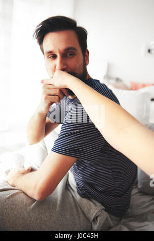 Uomo seduto sul letto, donna baciare la mano Foto Stock