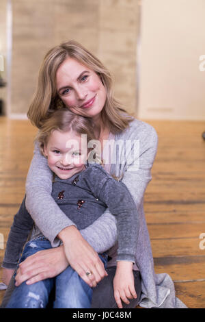 Ritratto di Madre e figlia seduta sul pavimento, sorridente Foto Stock
