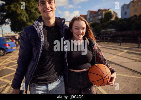 Due amici passeggiate all'aperto, giovane donna tenendo la pallacanestro, Bristol, Regno Unito Foto Stock