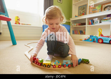 Toddler femmina giocando con il trenino sul pavimento nella sala giochi Foto Stock