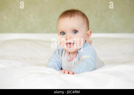 Ritratto di carino dagli occhi blu bambina giacente sul letto Foto Stock