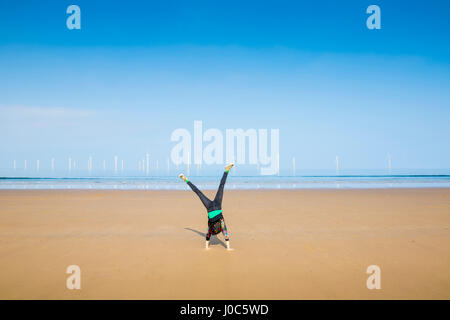 Donna matura facendo appoggiate su Redcar Beach, North Yorkshire, Regno Unito Foto Stock