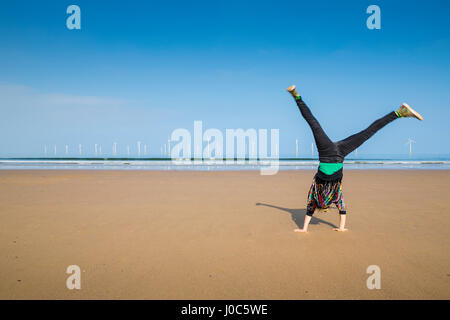 Donna matura facendo appoggiate su Redcar Beach, North Yorkshire, Regno Unito Foto Stock