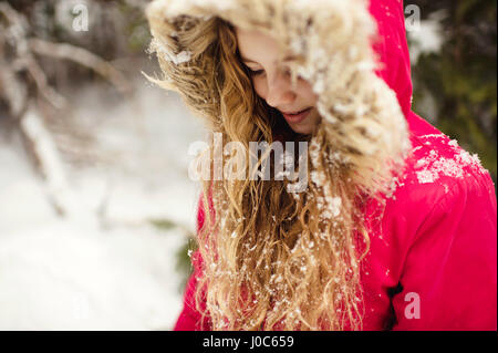 La ragazza di parka con la neve nei suoi capelli guardando verso il basso Foto Stock