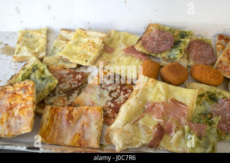 Assortimento di vari tipi di pizza tagliata in pezzi e arancine ripiene Foto Stock