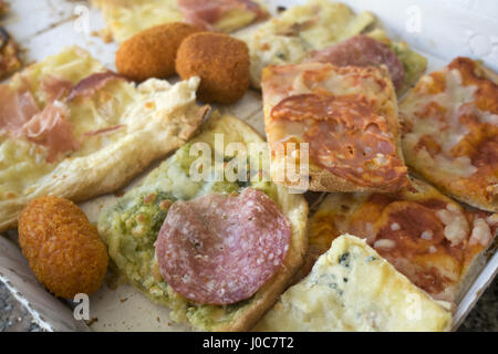 Assortimento di vari tipi di pizza tagliata in pezzi e arancine ripiene Foto Stock