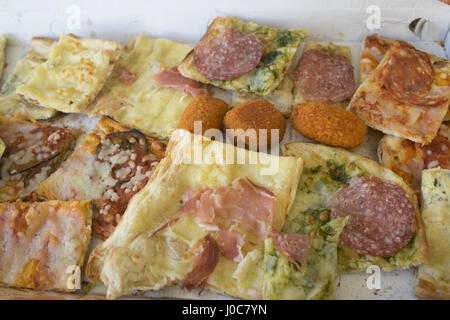 Assortimento di vari tipi di pizza tagliata in pezzi e arancine ripiene Foto Stock