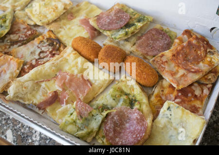 Assortimento di vari tipi di pizza tagliata in pezzi e arancine ripiene Foto Stock