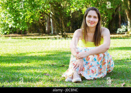 Seduto sull'erba nel parco Foto Stock