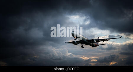 Vista dalla spiaggia dell'atterraggio aereo isolato sulla bellissima nuvoloso cercando drammatico sfondo cielo Foto Stock