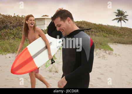 Bagnino maschio a chiacchierare con surfer sulla spiaggia Foto Stock