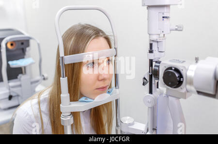 Piuttosto giovane donna con il suo occhi esaminati da un occhio medico di una lampada a fenditura Foto Stock