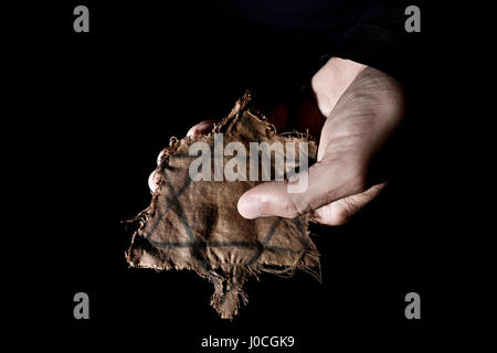 Primo piano di un lacero badge ebraica nella mano di un uomo Foto Stock