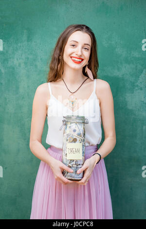 Donna che mantiene un flacone pieno di risparmio di denaro Foto Stock