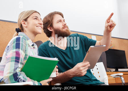 I colleghi di avvio alla ricerca di idea di soluzione nel lavoro di squadra utilizzando tablet Foto Stock