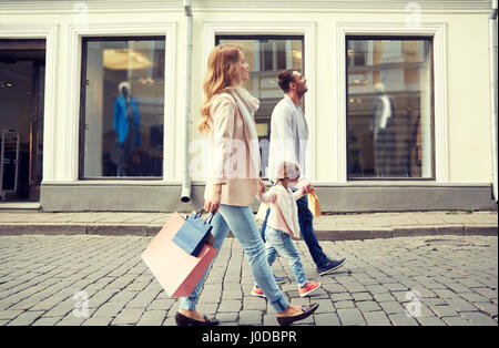 La famiglia felice con il bambino e di borse per lo shopping in città Foto Stock