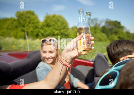 Felice di giovani donne con bevande in autovettura convertibile Foto Stock