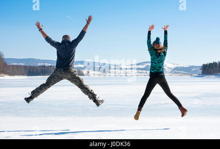 Happy amici saltando su un lago ghiacciato Foto Stock