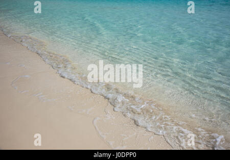 Calma il mare blu: piccola onda increspature giro a riva su una bella rosa di sabbia Bahamas Beach. Foto Stock