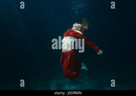 La donna in un abito rosso sul fondo sottomarino. Foto Stock