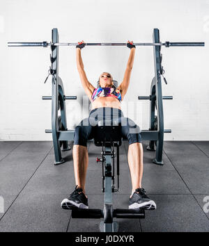 Giovani sportive giacenti e di esercitare con barbell in palestra Foto Stock