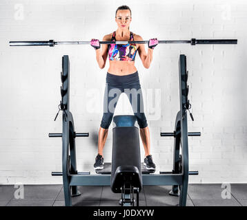 Sportive esercizio in palestra con barbell e guardando la fotocamera Foto Stock