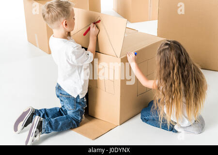 Carino piccolo ragazzo e ragazza casa di disegno sulla scatola di cartone Foto Stock