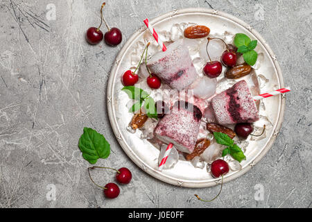 Il Cocco popsicles con ciliegie fresche e chia seme sulla piastra metallica. Vegan gelato, vista dall'alto Foto Stock