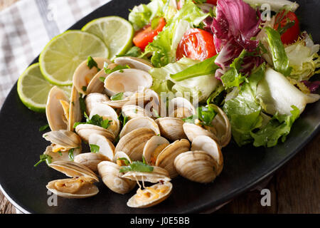 Delicatessen vongole con calce e insalata di verdure fresche close-up su una piastra orizzontale. Foto Stock