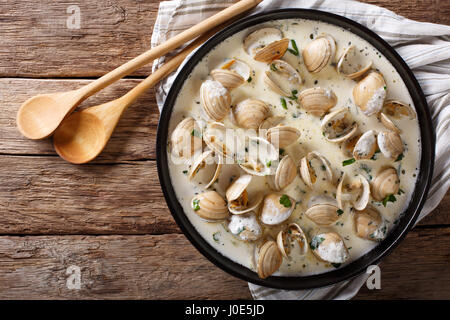 Delicatessen cibo: vongole stufati in crema con aglio e verdi di close-up su una piastra su un tavolo. vista orizzontale dal di sopra Foto Stock