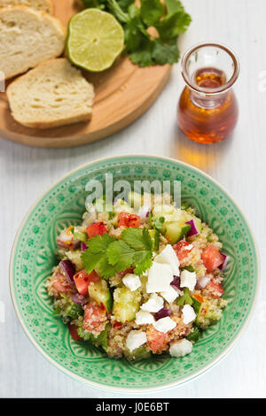 Tabulé con la quinoa, pomodori, cetrioli, guarnita con il formaggio feta e coriandolo Foto Stock
