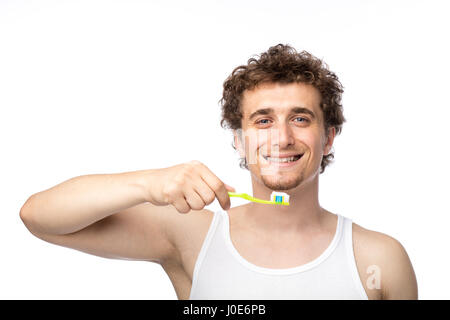 Curly divertente gli uomini con la canottiera bianca spazzolando i suoi denti con cura, isolato su bianco Foto Stock