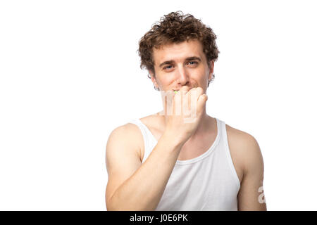 Curly divertente gli uomini con la canottiera bianca spazzolando i suoi denti con cura, isolato su bianco Foto Stock