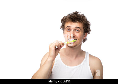 Curly divertente gli uomini con la canottiera bianca spazzolando i suoi denti con cura, isolato su bianco Foto Stock