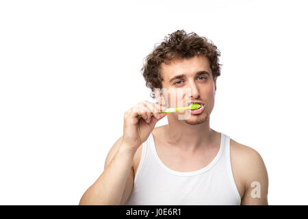 Curly divertente gli uomini con la canottiera bianca spazzolando i suoi denti con cura, isolato su bianco Foto Stock