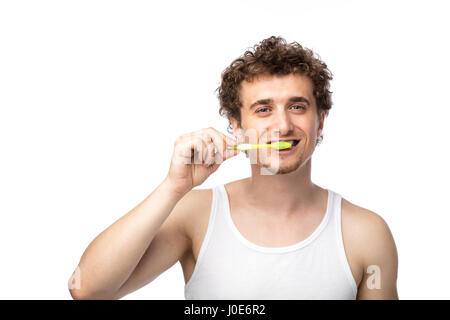 Curly divertente gli uomini con la canottiera bianca spazzolando i suoi denti con cura, isolato su bianco Foto Stock